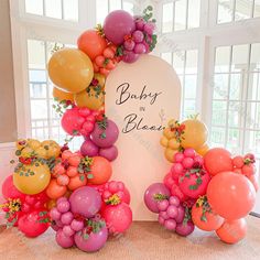 balloons and flowers are arranged around a sign for a baby's first birthday party