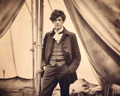 a sepia photograph of a man standing in front of a tent with his hands on his hips