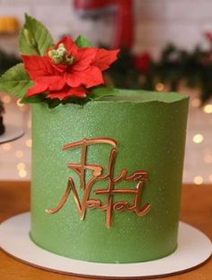 there is a green cake with gold lettering and a poinsetti on the top