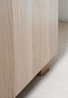 a close up view of a wooden cabinet with white carpet on the floor and side