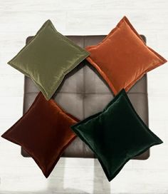 four different colored pillows sitting on top of a couch