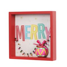 a red frame holds a christmas ornament with candy and the word merry on it