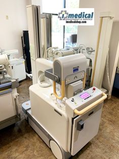 a hospital room with medical equipment in the foreground and windows on the other side