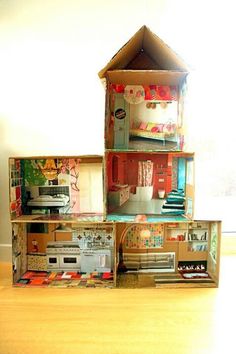 a doll house made out of cardboard boxes on top of a wooden floor next to a window