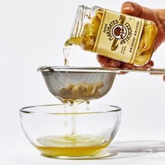 a person pours honey into a glass bowl with a strainer on the side