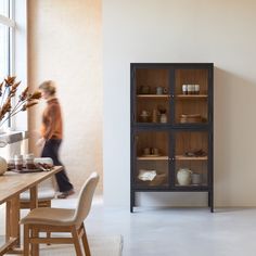 a blurry photo of a person walking in front of a cabinet with glass doors