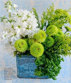 white and green flowers in an old tin can with the words edgewood written on it