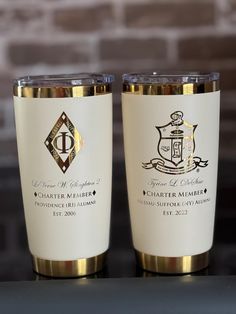 two white and gold colored cups sitting next to each other on top of a table