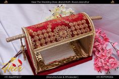 a red and gold purse sitting on top of a white table next to pink flowers