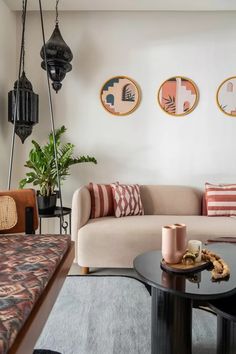 a living room with couches, tables and rugs in front of three paintings on the wall