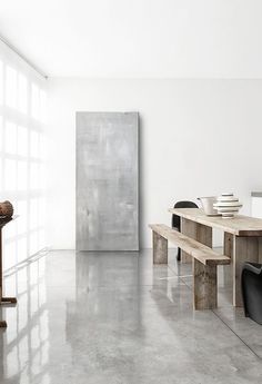 an empty room with a table and two chairs next to a large painting on the wall