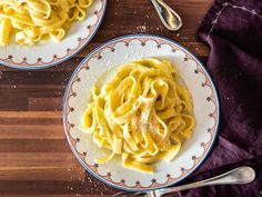 two plates of pasta on a wooden table