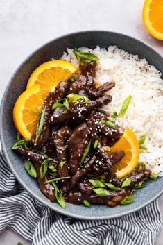 a bowl filled with rice, oranges and meat on top of it next to an orange slice