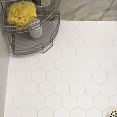 a bathroom with white hexagonal tiles and yellow sponge on the floor