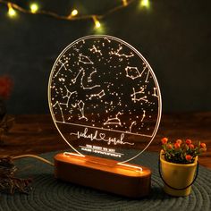 a personalized night light on a wooden stand next to a potted plant and string lights