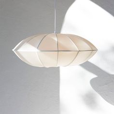 a white lamp hanging from a ceiling in a room with light coming through the window