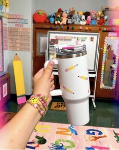 a person holding a coffee cup in their hand while sitting at a table with toys