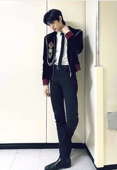 a young man leaning against a wall wearing a suit and tie