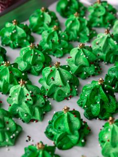 there are many green frosted christmas trees on the cookie sheet and sprinkles