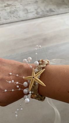 a person's arm with a starfish and pearls bracelet on top of it