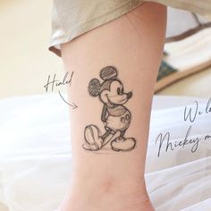 a person with a mickey mouse tattoo on their foot and the other side of her leg