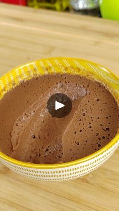 a yellow bowl filled with chocolate pudding on top of a wooden table