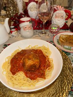 a white plate topped with spaghetti and meatballs on top of a table next to wine glasses