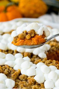 a spoon full of marshmallows on top of a casserole dish