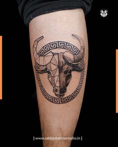 a bull head tattoo on the leg with geometric lines and an ornament around it