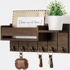 a wooden shelf with key hooks and keys hanging from it's sides, next to a potted plant