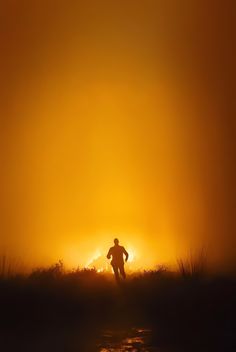 the silhouette of a person running through foggy grass