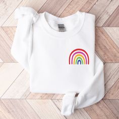 LITTLE RAINBOW GILDAN UNISEX SWEATSHIRT **IMPORTANT** These are print-on-demand sweatshirts, so please keep in mind that they can take up to 7-10 business days to be fulfilled and 3-6 business days to be shipped. Sometimes fulfillment can happen very quickly and sometimes longer than usual. The typical turnaround for production and shipping is 8-12 days. The Gildan 18000 Sweatshirts are one of the most popular heavy-weight unisex sweatshirts in the world. They're made of 50% cotton & 50% polyest Trendy White Crew Neck Sweater, White Cotton Sweater With Graphic Print, Multicolor Cotton Tops With Ribbed Cuffs, White Cotton Crew Neck Sweater, Rainbow Long Sleeve Sweatshirt For Winter, Rainbow Long Sleeve Sweatshirt For Fall, Long Sleeve Rainbow Sweatshirt For Fall, Rainbow Cotton Sweatshirt For Winter, White Rainbow Print Crew Neck T-shirt