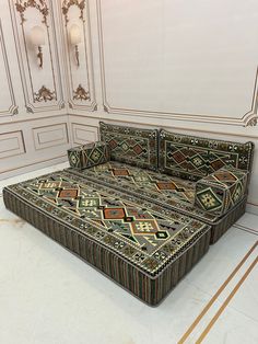 an ornately designed bed in the middle of a room with white walls and gold trimmings