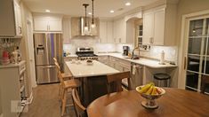 a kitchen filled with lots of counter top space and white cabinets next to a dining room table