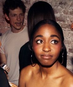 a woman with large hoop earrings standing next to other people