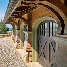 an arched wooden door on the side of a brick building next to a stone walkway