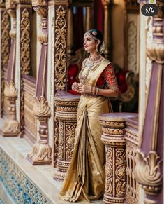 a woman in a gold and red sari standing on the balcony of a building