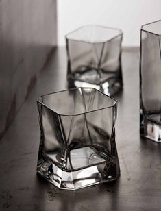 three clear glass vases sitting on top of a wooden table next to each other