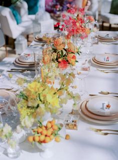 a long table is set with flowers and plates