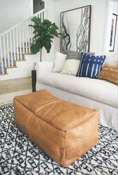 a living room filled with furniture and a large plant on top of a rug in front of a white couch