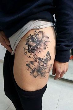 a woman's thigh with butterflies and flowers tattoo on her leg, while she is wearing