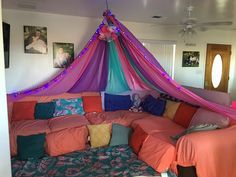 a bed with pink, blue and orange sheets on it