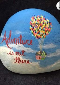 a painted rock that says adventure is out there with a hot air balloon in the sky