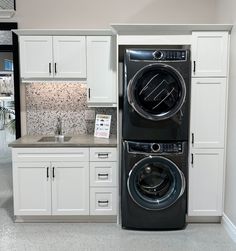 a washer and dryer in a room with white cabinets