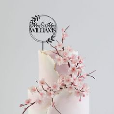 a white cake with pink flowers on top and a sign that says mr and mrs williams