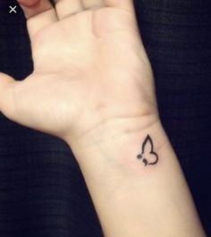 a person's hand with a small tattoo on the middle of their left wrist