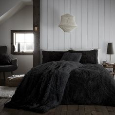 a bedroom with white walls and wood flooring is decorated in black and grey tones