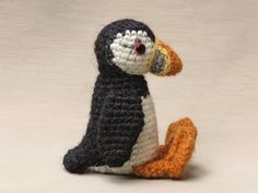 a crocheted penguin sitting on the ground with it's beak open and eyes wide open