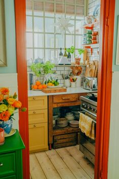 a kitchen with orange and green accents, yellow cabinets and an open door that leads to the outside