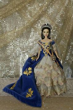 a doll is sitting on the floor wearing a blue and gold dress with a tiara